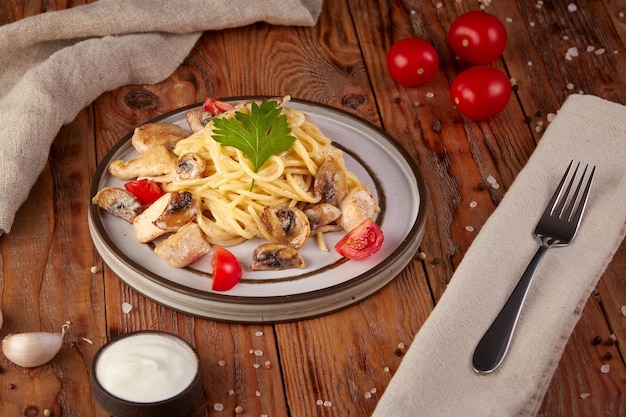 Pasta with chicken and mushrooms, Italian cuisine, wooden background