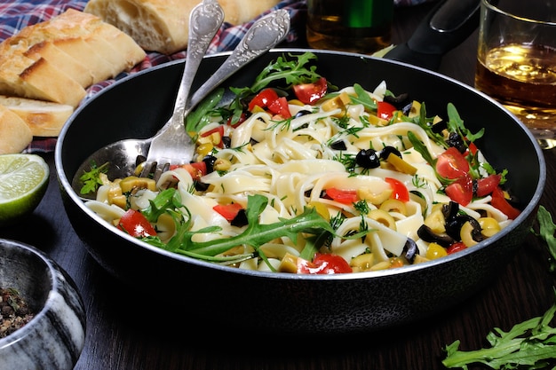 Pasta with crushed olives and cherry tomatoes, arugula. Horizontal shot.