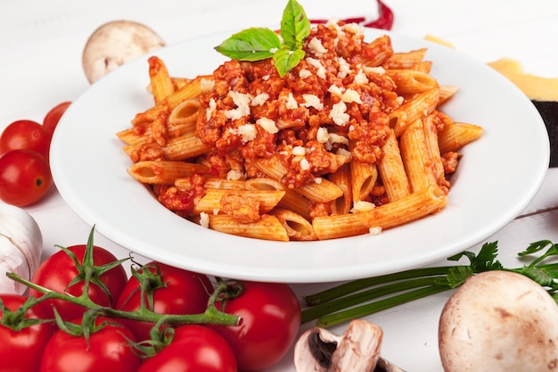 Pasta with meat, tomato sauce and vegetables on the table