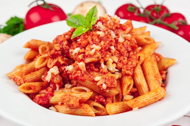 Pasta with meat, tomato sauce and vegetables on the table