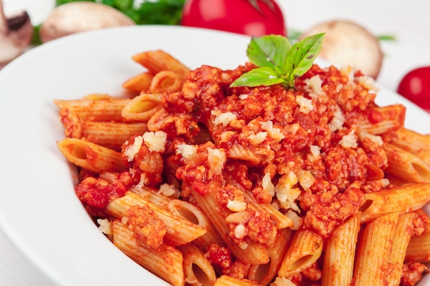 Pasta with meat, tomato sauce and vegetables on the table