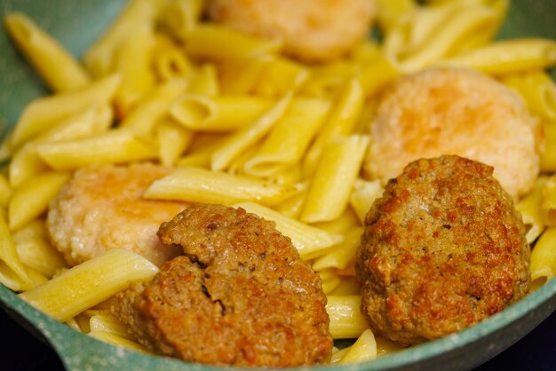 Pasta with meatballs in skillet closeup