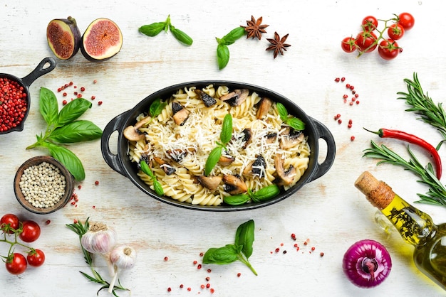 Pasta with mushrooms parmesan cheese and basil in a black pan Top view