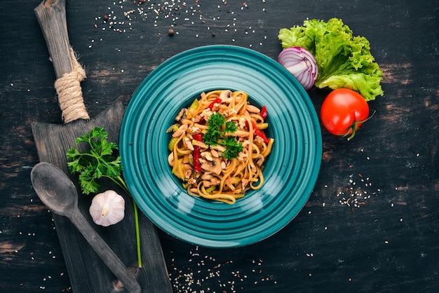 Pasta with mushrooms and vegetables Italian cuisine On a wooden background Top view Copy space