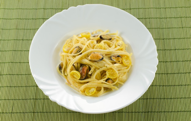 Pasta with mussels lying on a white plate on a green napkin in the restaurant