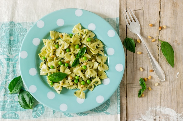 Pasta with pesto sauce, green peas and basil on a wooden table