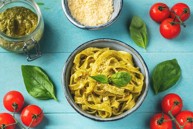 Pasta with pesto sauce, ingredients and spices on a table with a dish. 