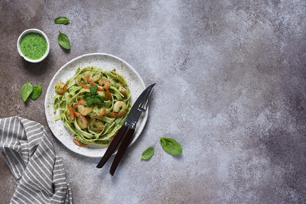 Pasta with pesto and shrimp on a plate on the kitchen table top view