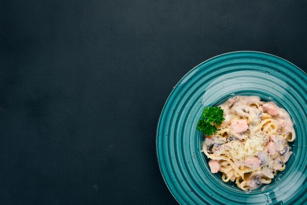 Pasta with salmon and mushrooms Italian cuisine On a wooden background Top view Copy space