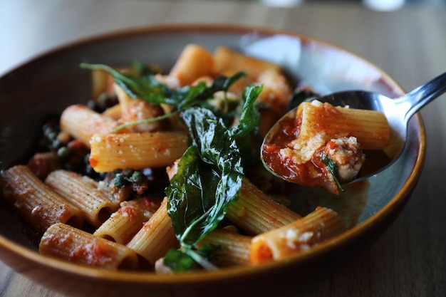 Pasta with sausage in tomato sauce on wood background , italian food