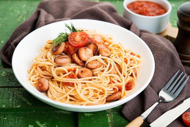 Pasta with sausages and tomato sauce on a rustic background, close up