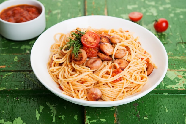 Pasta with sausages and tomato sauce on a rustic background, close up