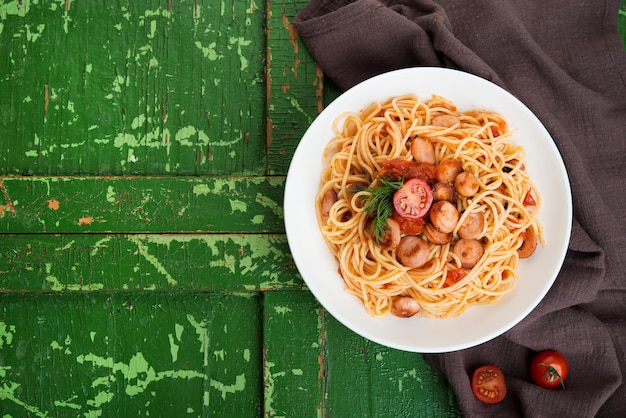 Pasta with sausages and tomato sauce on a rustic background, top view