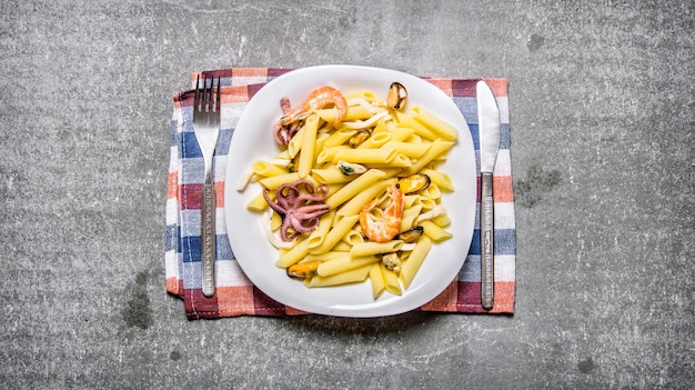 Pasta with seafood on a plate on the fabric on the stone table