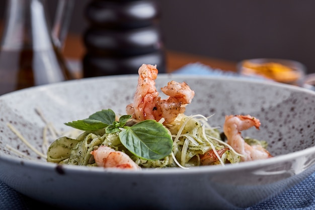 Pasta with shrimps and basil sauce. Italian cuisine. Traditional Italian pasta with shrimps and basil, olive oil and pesto sauce.