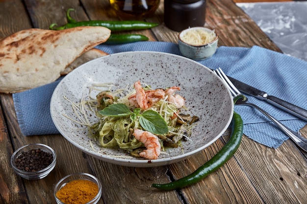 Pasta with shrimps and basil sauce. Italian cuisine. Traditional Italian pasta with shrimps and basil, olive oil and pesto sauce.