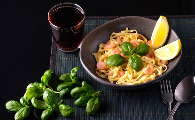 Pasta with shrimps, basil and tomatoes on a dark background