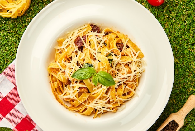 pasta with sun-dried tomatoes served in a plate with parmesan cheese and basil