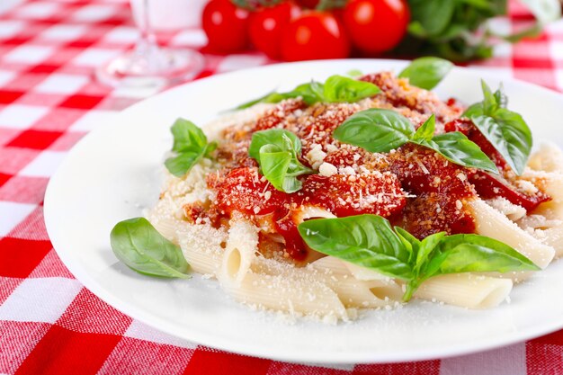 Pasta with tomato sauce and basil on table close up