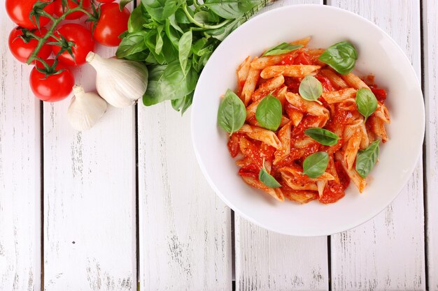 Photo pasta with tomato sauce and basil on table close up