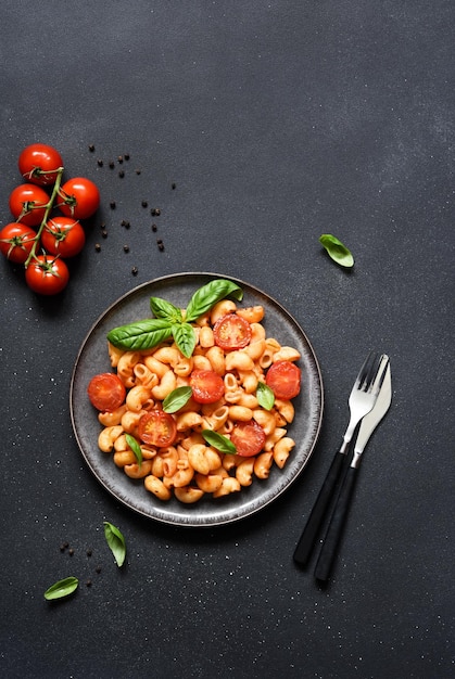 Pasta with tomato sauce and cherry tomatoes on a concrete background top view with space for text