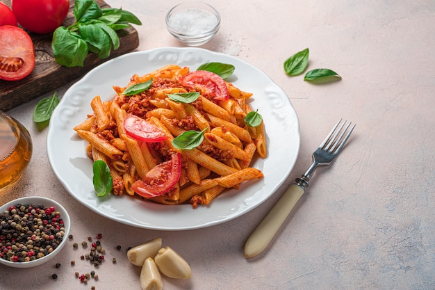 Pasta with tomato sauce, tomatoes and basil on a light gray background. Italian dish. Side view, copy space.