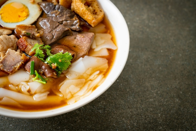 paste of rice flour or boiled Chinese pasta square with pork in brown soup. Asian food style