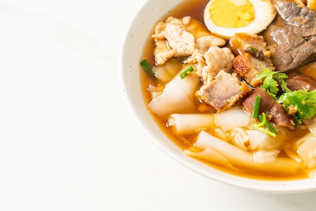 paste of rice flour or boiled Chinese pasta square with pork in brown soup - Asian food style