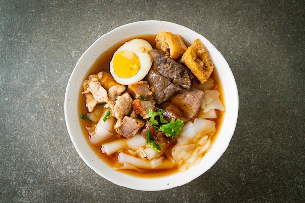 paste of rice flour or boiled Chinese pasta square with pork in brown soup - Asian food style