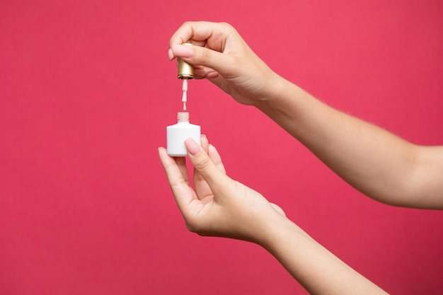 pastel color nail polish bottle with drop on pink background