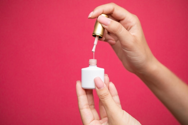 pastel color nail polish bottle with drop on pink background