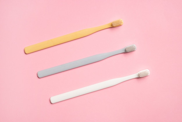 Pastel color toothbrushes on pink background .Simple composition for cleaning teeth and morning routine top view