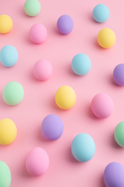 Pastel colored Easter eggs scattered on pink background. Easter Day colorful abstract pattern, flat lay.