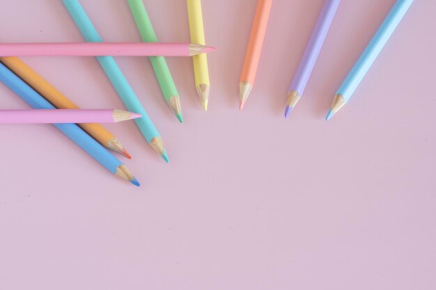 Pastel colored pencils top view on pink background illustration concept education and back to school