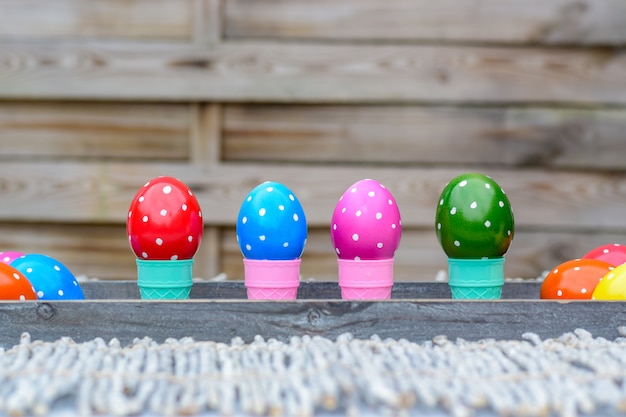  Pastel and colorful Easter eggs in ice cones on a wooden background.