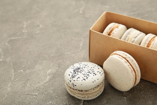 Pastel macaroons in box on grey background Space for text