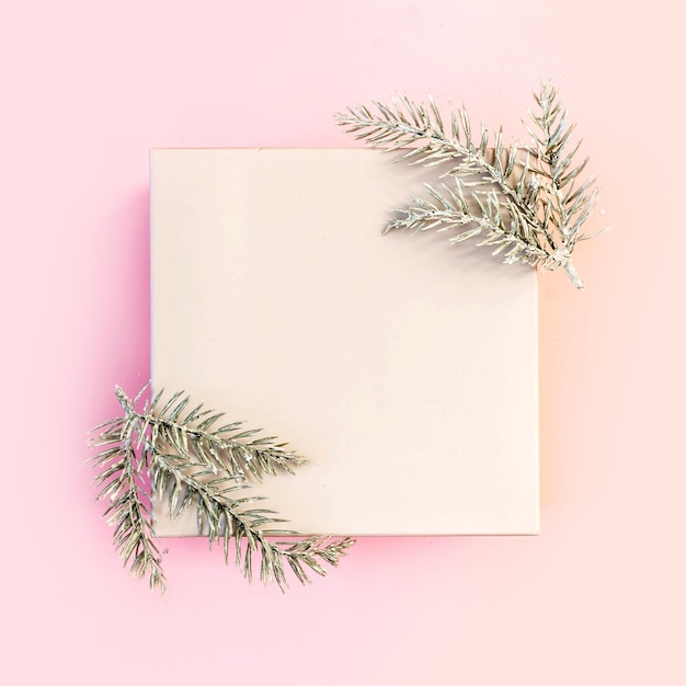 Pastel pink background with snowy fir branches and copy space for text. Christmas, festive or winter background. Top view, flat lay, mock up