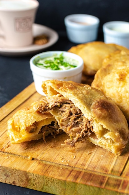 Pastelito traditional venezuelan food in dark backgroud, three sauce and coffee