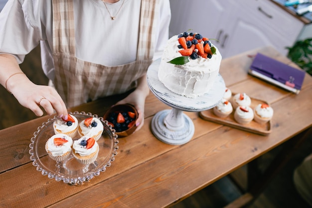 Pastry chef confectioner young caucasian woman with cake on kitchen table