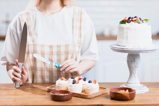 Pastry chef confectioner young caucasian woman with cake on kitchen table