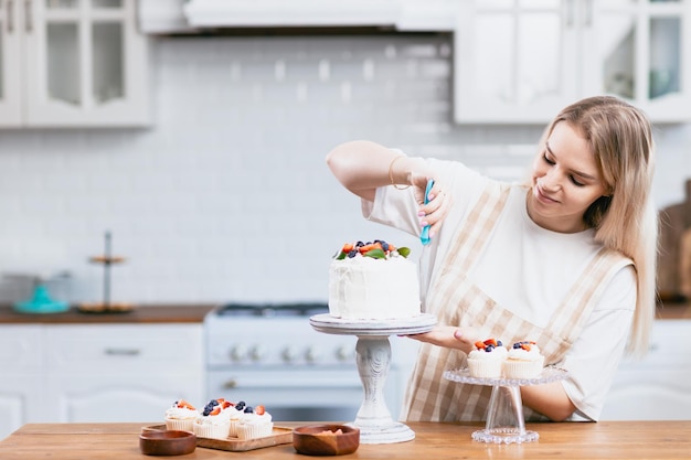 Pastry chef confectioner young caucasian woman with cake on kitchen table