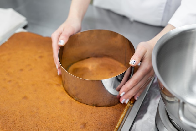 Pastry chef cuts out a cake cake from a biscuit