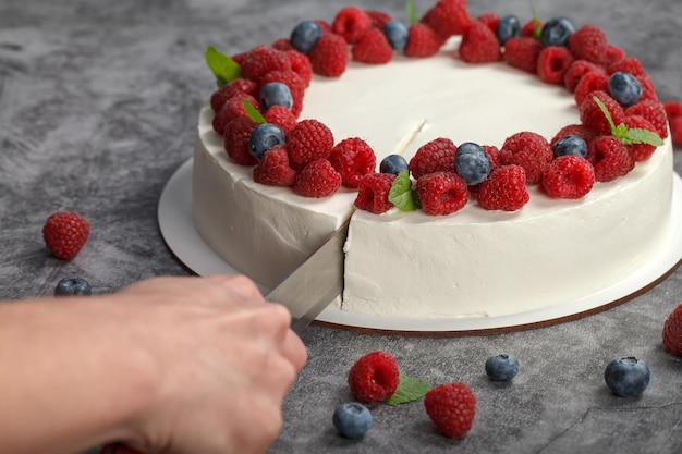 Pastry chef cuts raspberry cake with a knife