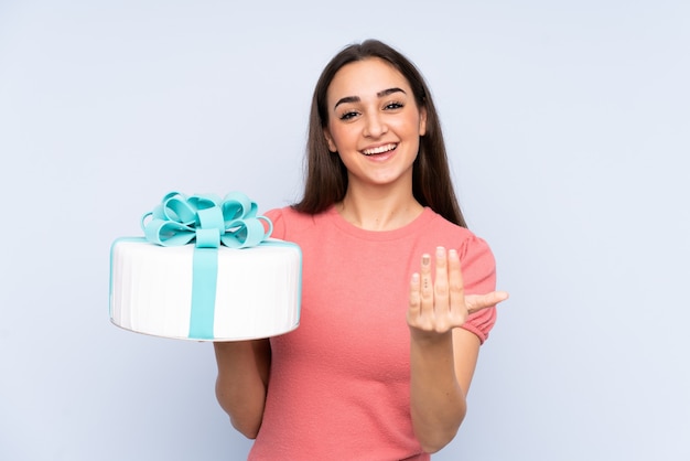 Pastry chef holding a big cake isolated inviting to come