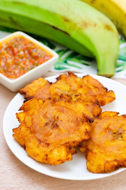 Patacones or fried tostones of green or ripe planta with hogado Colombian food