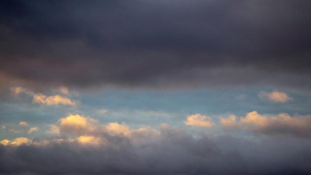 A patch of sky illuminated by the evening sun shines through the dark blue clouds