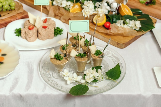 Pate in small cups on a plate decorated with flowers The table is with a beautiful white tablecloth