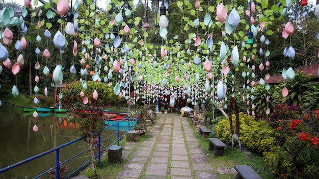 Pathway decorated with plastic accessories and plastic leaves with a lake on the left and ornamental plants on the right