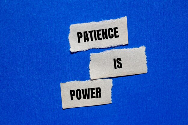 Photo patience is power message written on ripped torn paper peices on blue background conceptual patience is power symbol copy space