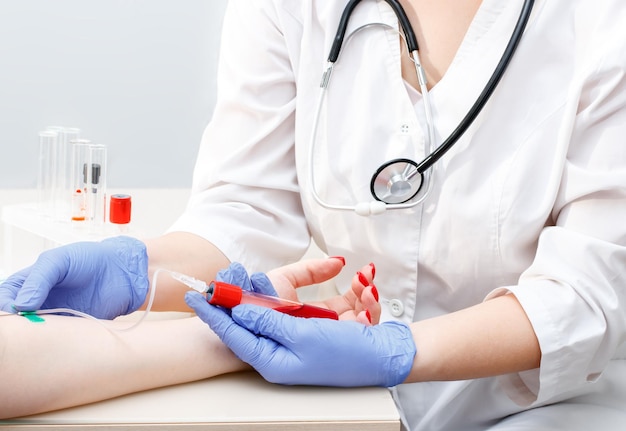 Patient gives blood for analysis to a medical laboratory A syringe in the hands of a nurse Closeup